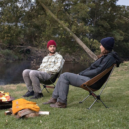 couple qui parlent près du feu de camp dans leur chaise camping