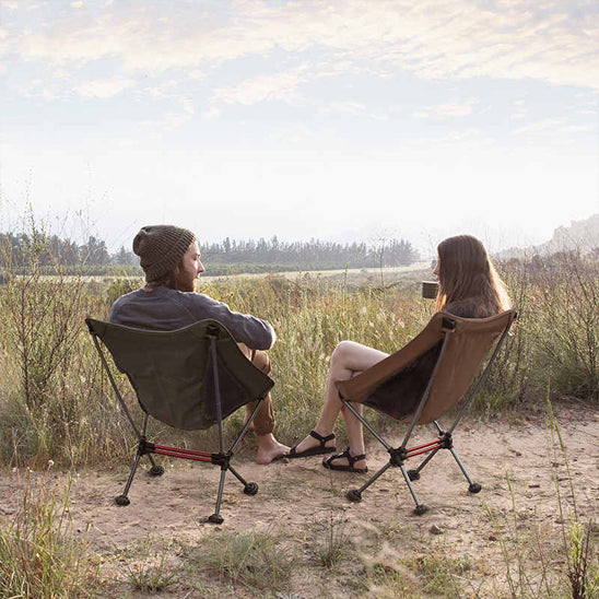 couple dans leur chaise camping installées dans le sable en buvant un café