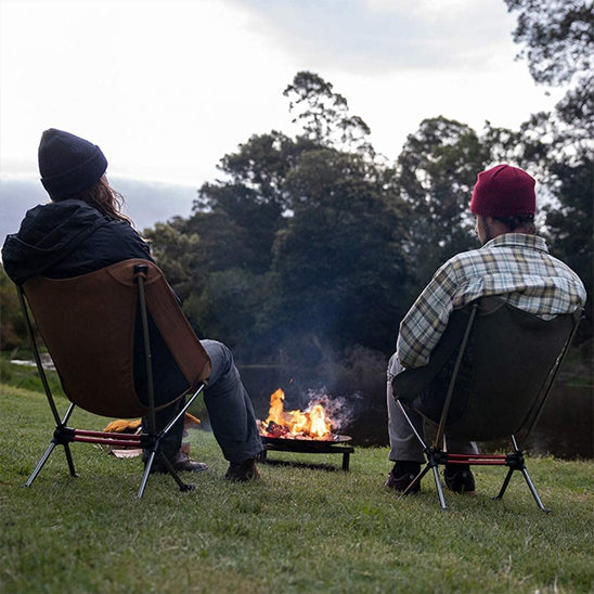 deux personnes qui regardent feu de camp dans leur chaise camping