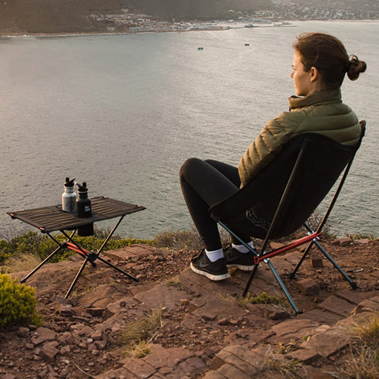femme assise devant un lac dans sa chaise de camping