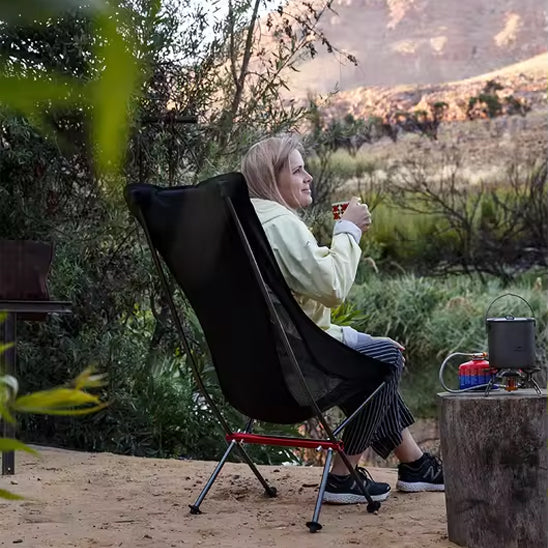 femme en plein air qui boit un bon café chaud assise dans sa chaise de camping