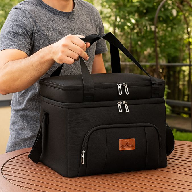 homme tenant une glaciere souple noir sur une table extérieur