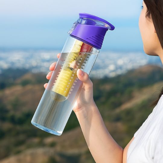 femme qui tient une gourde plastique infuseur violet dans sa main en plein air