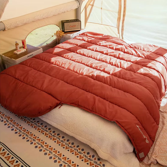 sac de couchage rouge déplié sur un matelas dans tente
