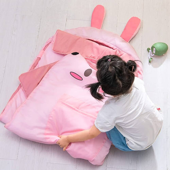 jeune fille qui plie un sac de couchage enfant pour le transporter