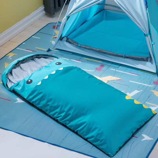 sac de couchage enfant bleu sur le sol prĂšs d'une tente