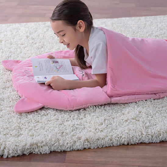 jeune fille qui lit un livre dans son sac de couchage enfant