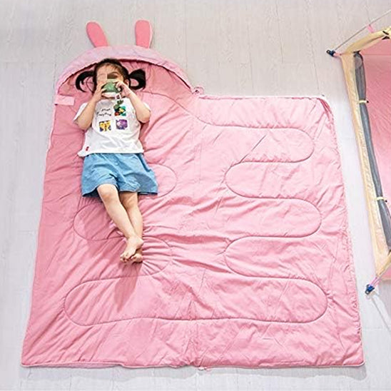 sac de couchage rose déplié sur le sol avec une ptite fille dessus