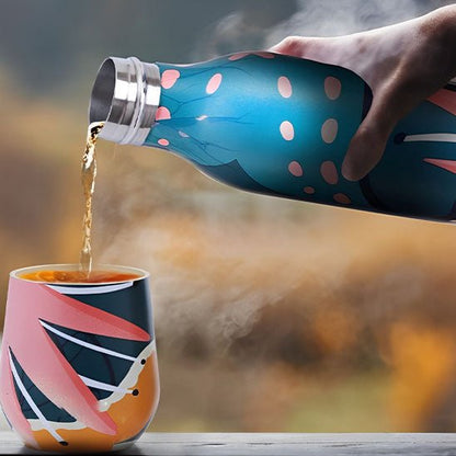 bouteille isotherme bleu versant de l'eau chaude dans une tasse de couleur multicolore