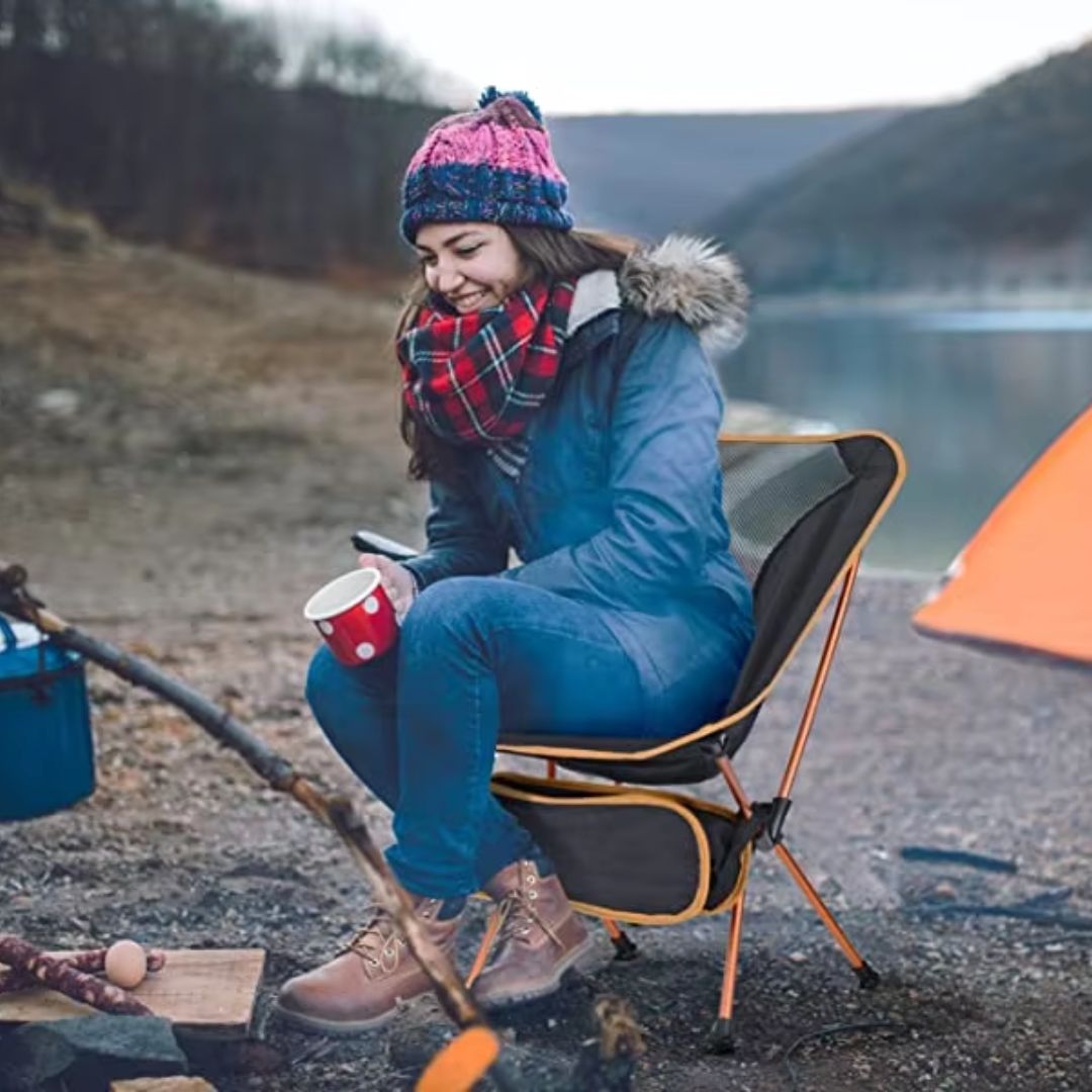 femme-assise-dans-chaise-pliante-camping-orange-compact