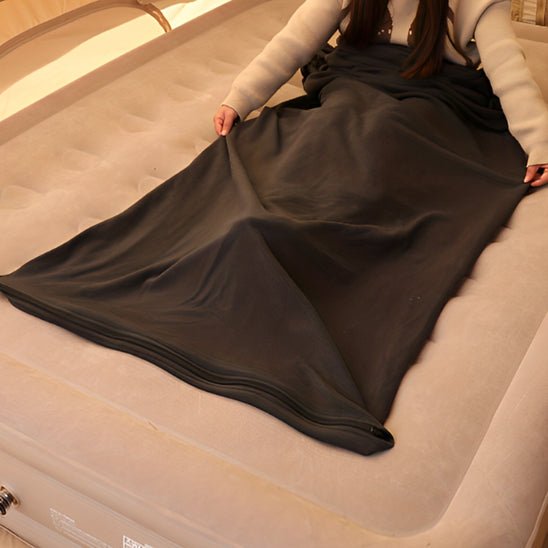 une-fille-sinstallant-sur-un-matelas-avec-son-drap-pour-sac-de-couchage-brun