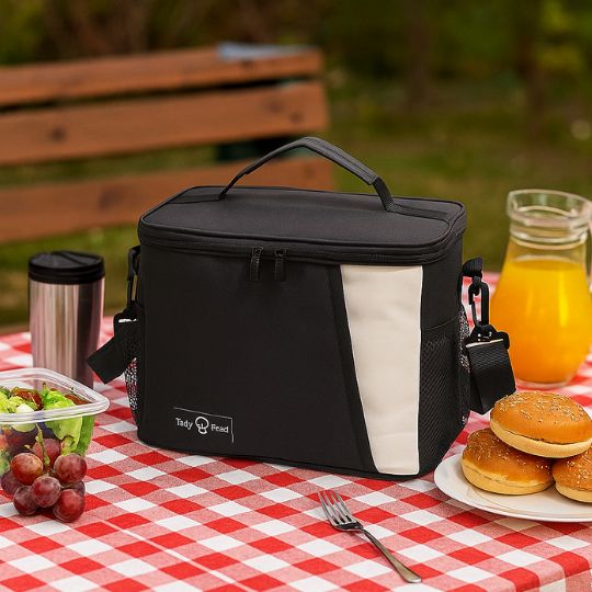 présentation d'une glaciere souple noir et blanche sur une table avec d'autre aliments en plein air
