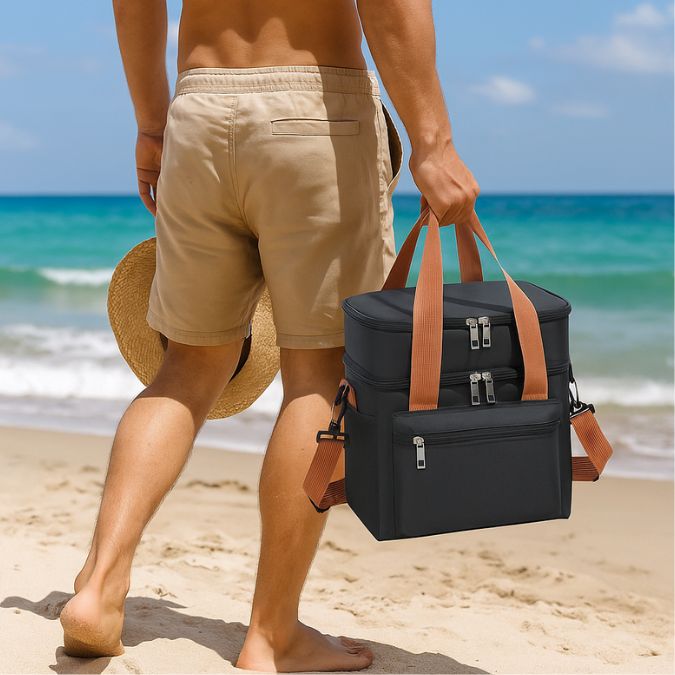 homme qui tient une glacière souple noir sur une plage au soleil