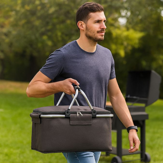 homme en plein air transportant une glaciere souple noir avec un bbq en arrière