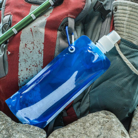 une gourde souple bleu accroché à un sac de rando