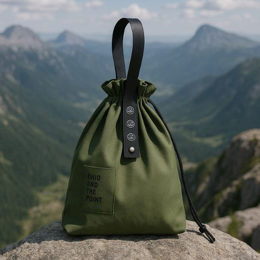 un lunch bag isotherme vert en toile sur un rocher au sommet d'une montagne