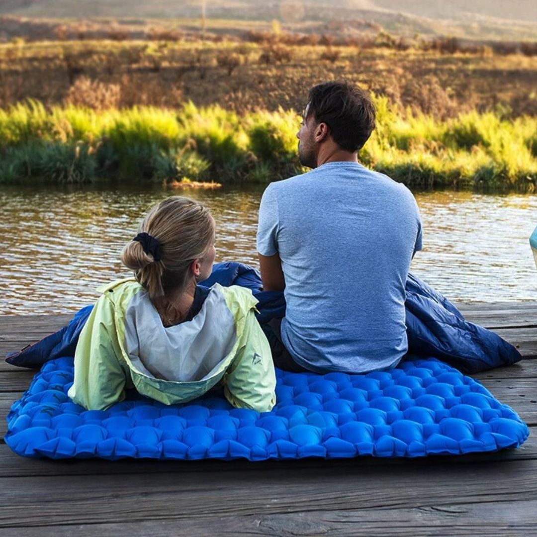 un-couple-regarde-le-paysage-confortablement-installe-sur-un-matelas-de-camping-bleu