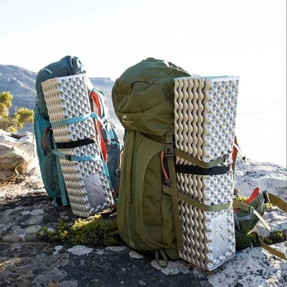 sac a dos au sommet d'une montagne avec des matelas trekking attachés à eux