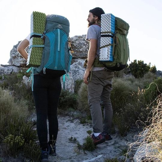 couple au sommet d'une montagne qui marche avec leur matelas trekking attaché au sac à dos