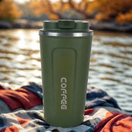 mug-thermos-vert-sur-une-couverture-a-cote-de-riviere