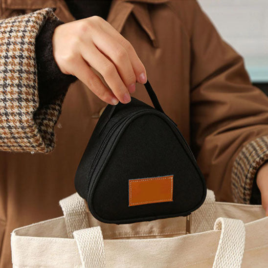 un petit sac isotherme noir tenu par la main d'une femme vêtue d'un manteau