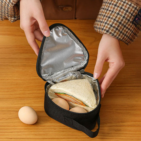 femme qui ouvre un petit sac isotherme noir en forme de triangle avec un sandwich a l'intérieur