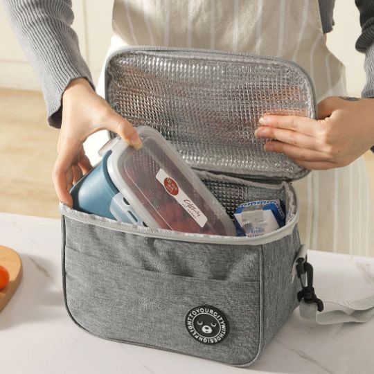 personne qui met un lunch box dans une petite glaciere repas
