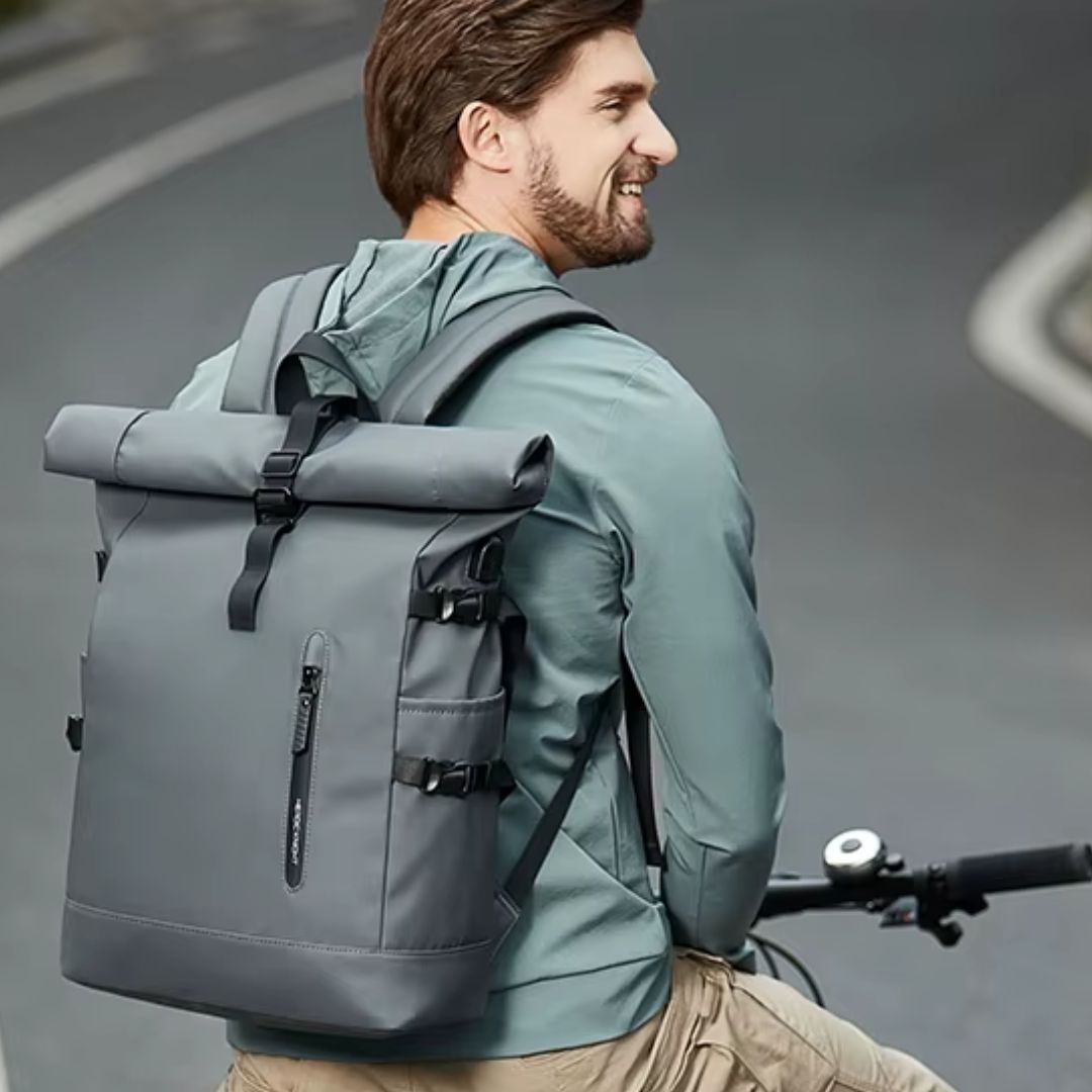 homme-heureux-à-vélo-avec-un-sac-a-dos-etanche-gris-sur-le-dos