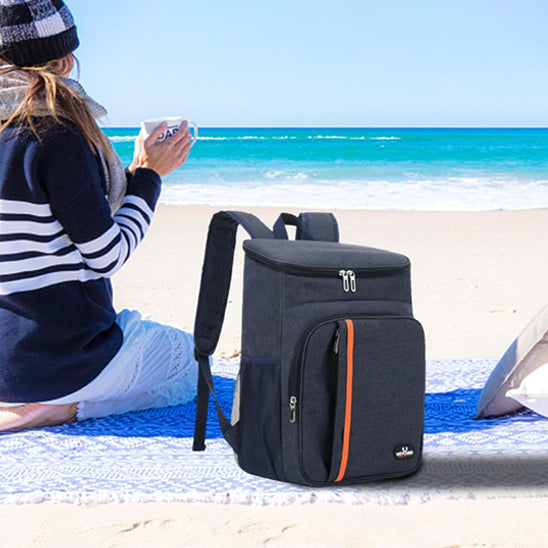 sac-a-dos-isotherme-posé-sur-le-sable-sur-une-plage-avec-une-femme-à-côté