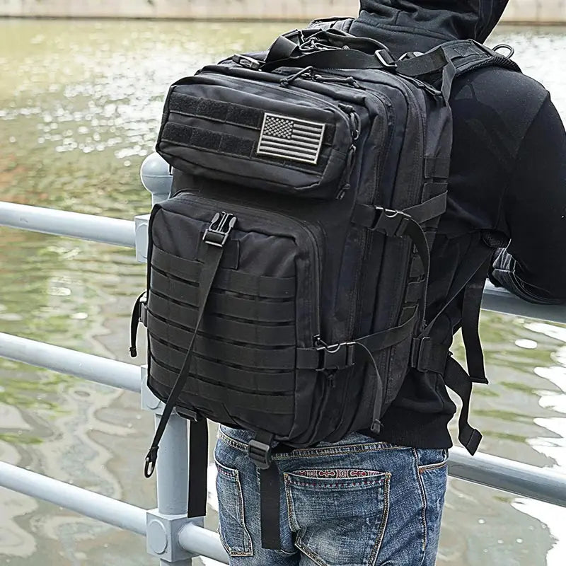 homme-portant-un-sac-à-dos-militaire-noir-sur-le-bord-de-leau