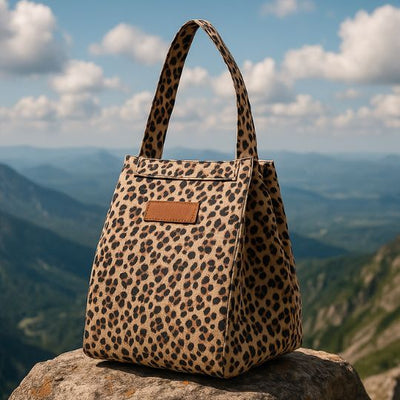 présentation d'un sac a la couleur de leopard sur un rocher au sommet d'une montagne
