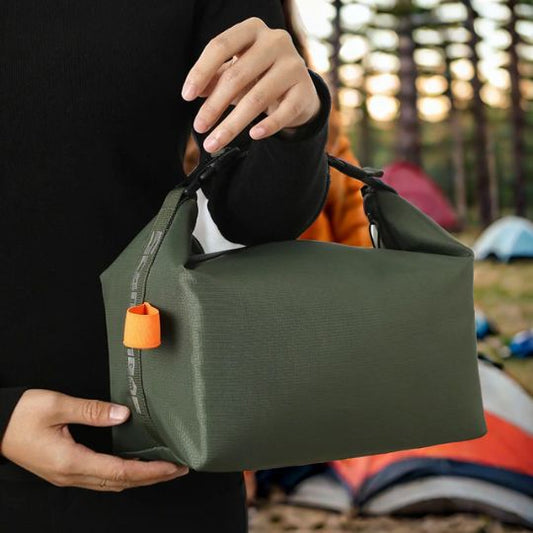 sac-isotherme-repas-vert-en-camping-tenu-par-la-main-avec-tentes-en-arriere