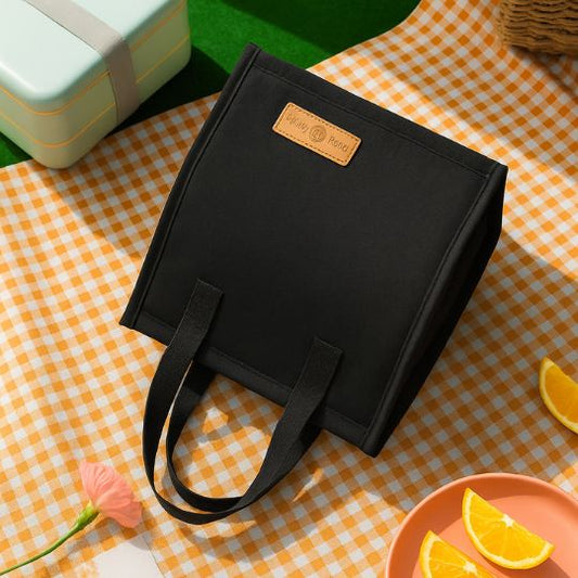 un sac lunch box noir déposé sur un tapis de camping