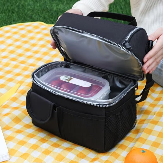 un randonneur qui ouvert le compartiment principal d'un sac repas isotherme noir à fermeture Éclair