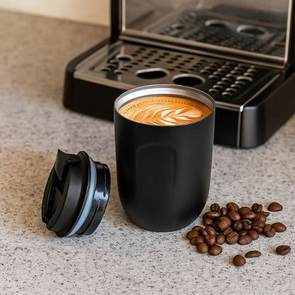 une tasse isotherme noir près d'une machine a café