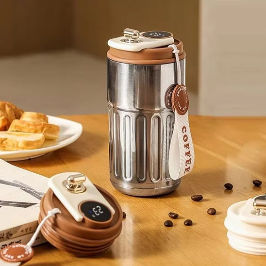 tasse thermos argent déposé sur une table