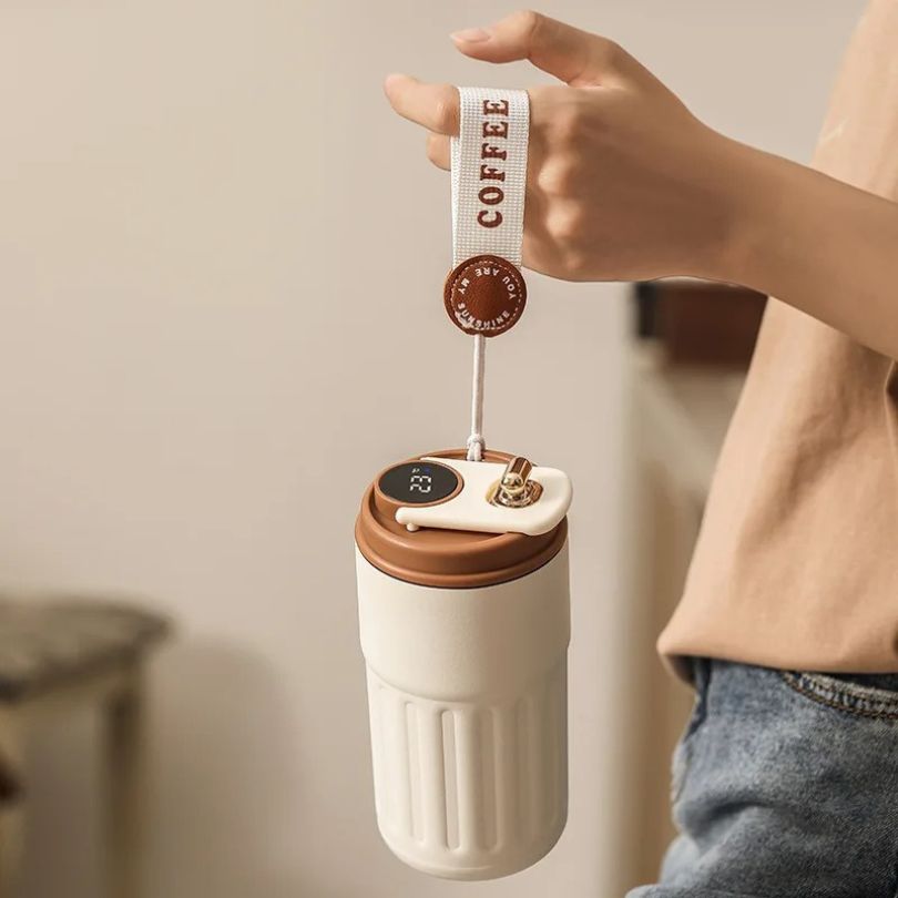 personne qui tient une tasse thermos par la anse