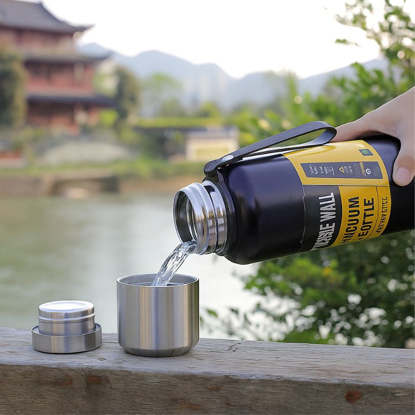 un thermos noir verse de l'eau fraiche dan sa tasse intégrée 